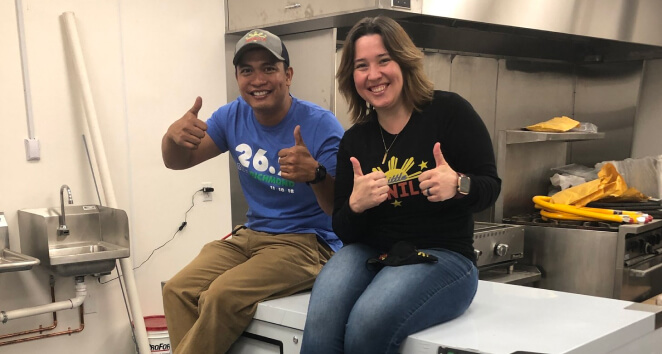 Man and woman giving thumbs up in commercial kitchen