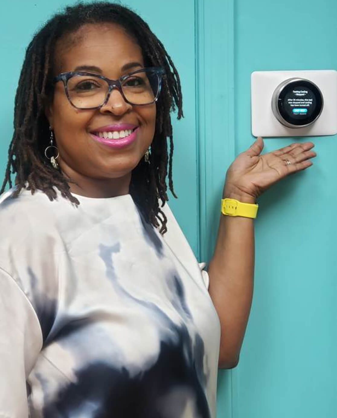 Woman in glasses standing in front of Smart Thermostat