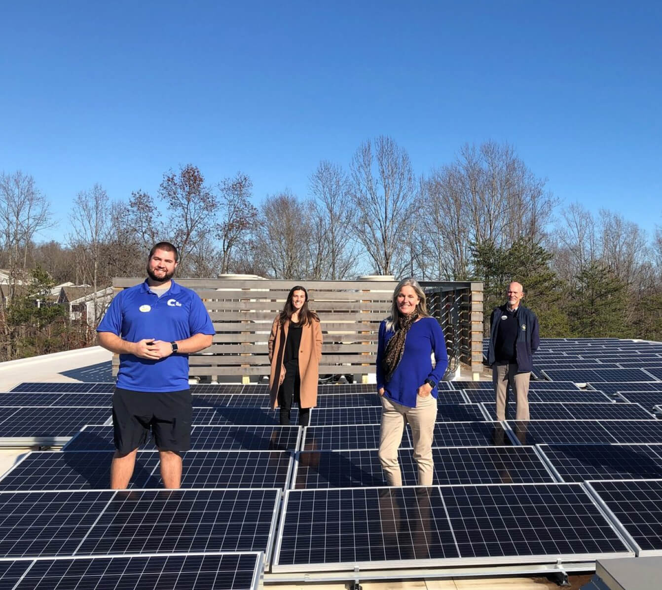 Four people standing on a rooftop solar installation